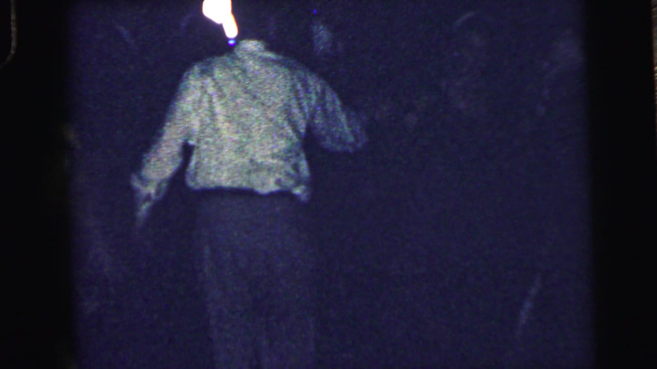 1964 Camden 8mm frame showing a man in a light shirt and dark trousers dancing under dim blue-purple lighting.