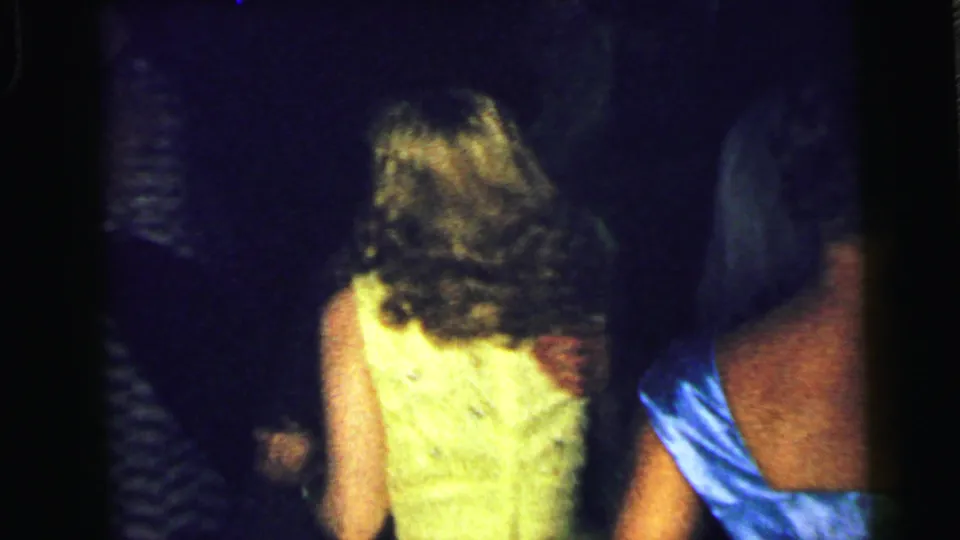 A rear view shows women in yellow and blue formal dresses dancing in the Camden party footage, framed by dark film edges.