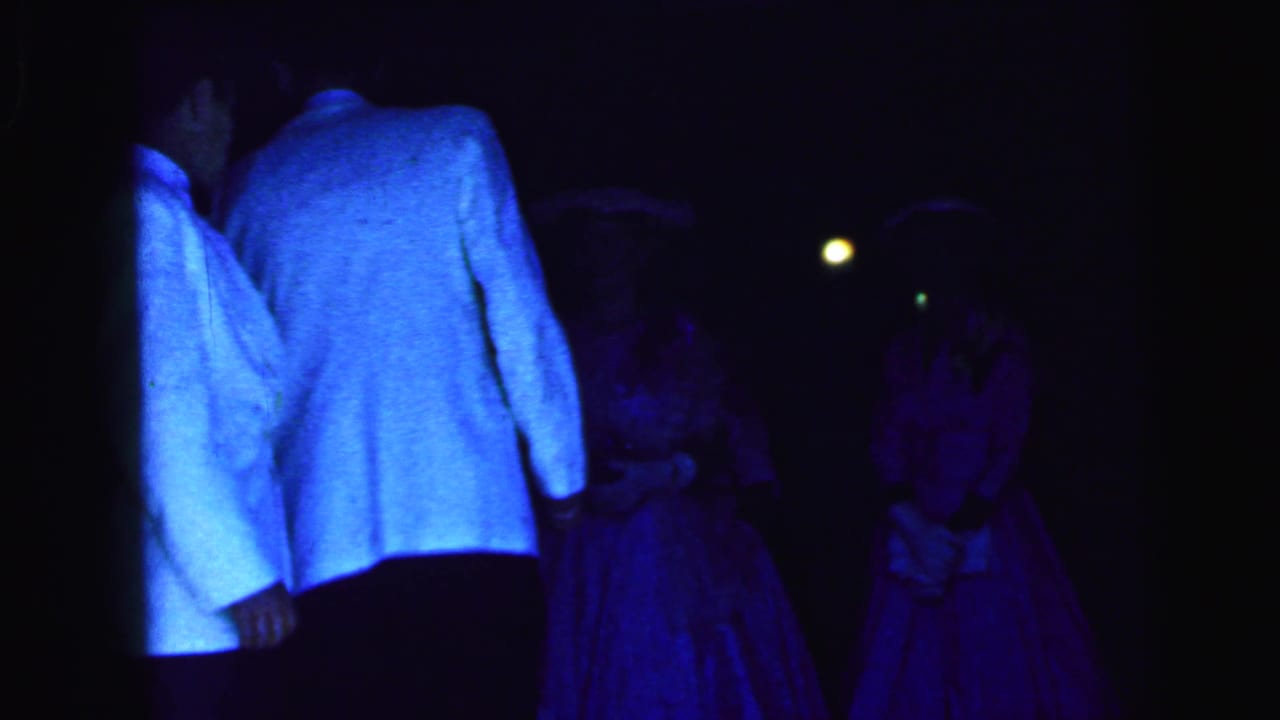 Dimly lit reception dancers seen mostly from behind under blue and purple light.