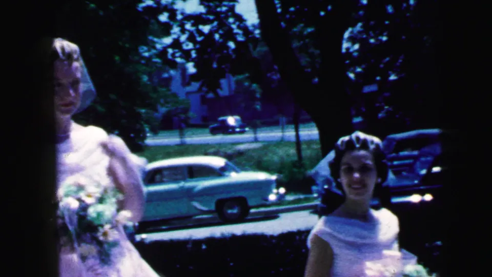 Brides in veils and white dresses pose near a Camden street, with mid-century cars visible behind them in 1964.