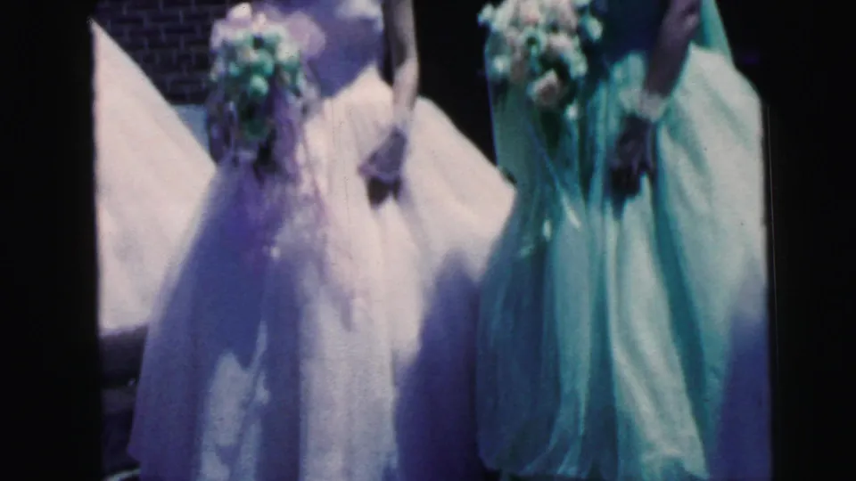 Close, cropped 8mm view of bridesmaids and bouquets outside a Camden church during a 1964 wedding gathering.
