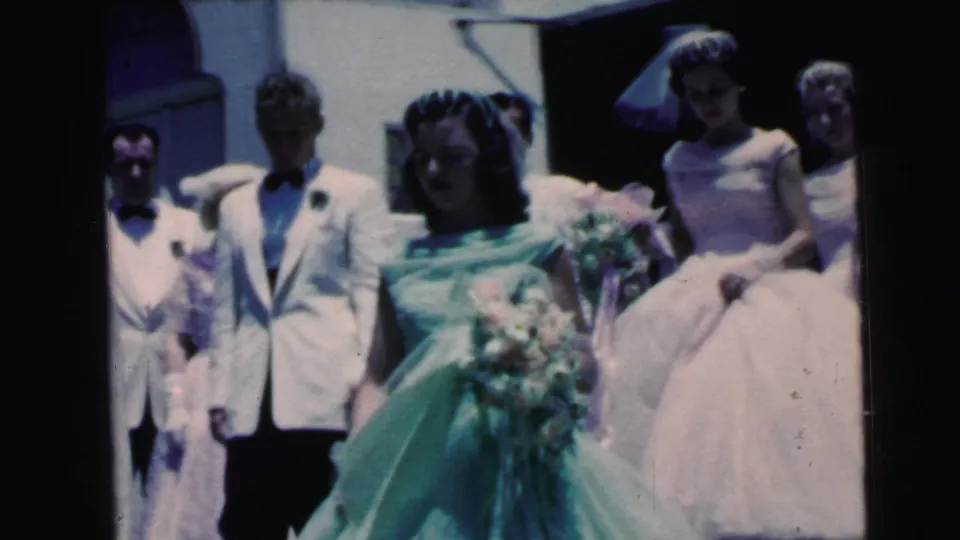 1964 Camden wedding-party frame with bride in green gown, groom in a white jacket, attendants, veils, bouquets, and pale formal dresses.