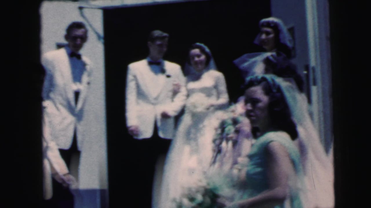 1964 Camden wedding scene with the bride and groom in the doorway and a bridesmaid carrying flowers in front.