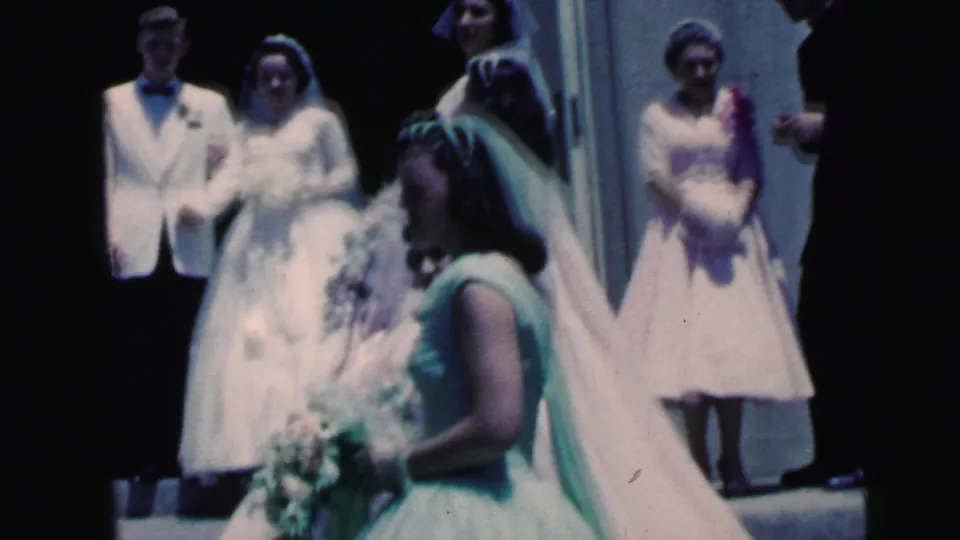 1964 Camden wedding footage with bride, groom, bridesmaids, veils, bouquets, and guests arranged near a bright doorway.