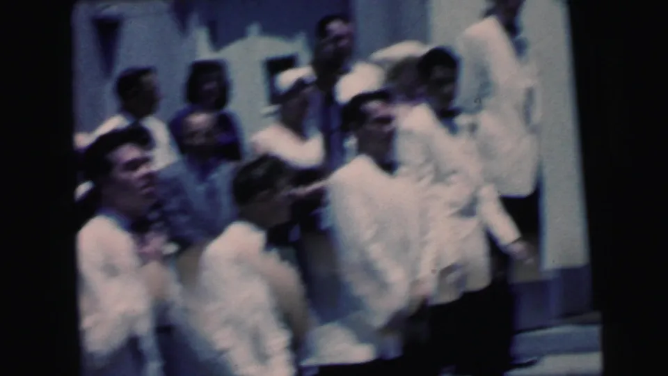 The Camden wedding party shifts position on the steps, with white-jacketed men and guests visible in soft 8mm focus.