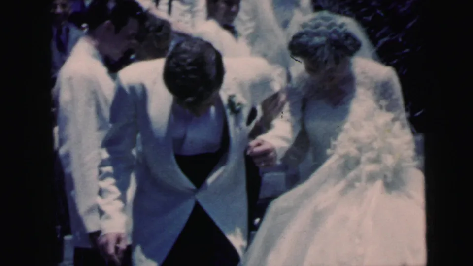 Close 8mm view of the newly married couple walking together in Camden, New Jersey, with guests surrounding them.