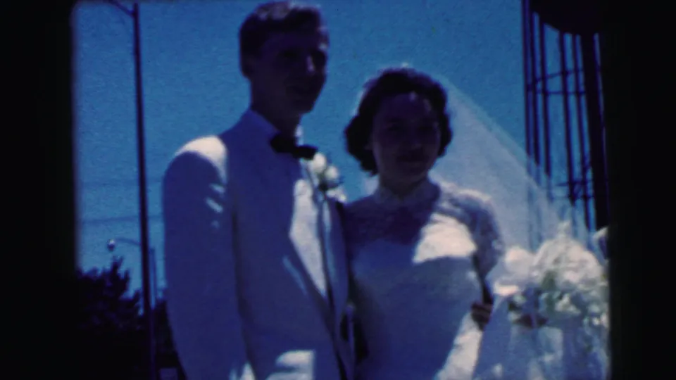 1964 Camden wedding frame showing the couple standing close together in shadow, with the bride's bouquet and veil visible.