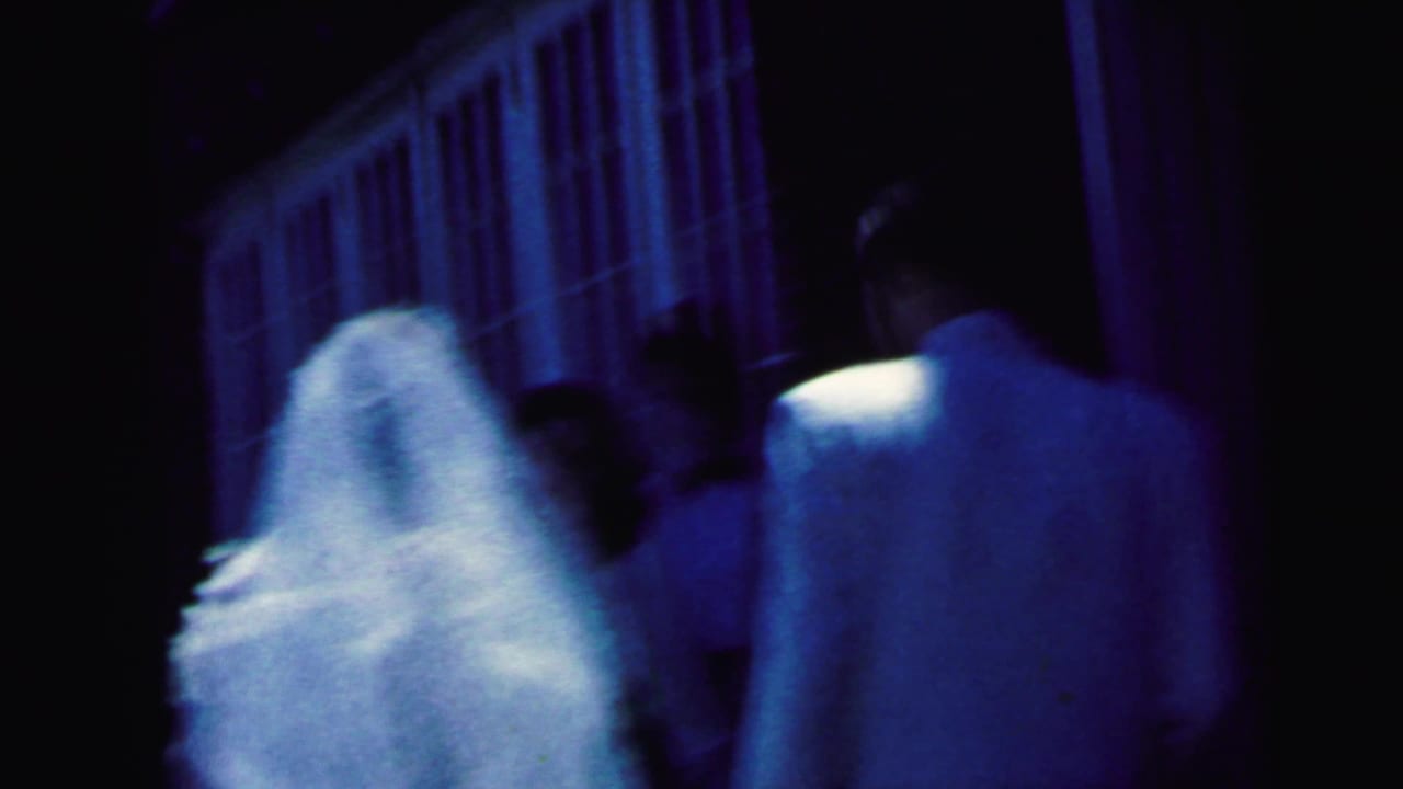 Bride and groom seen from behind walking toward a dark doorway.