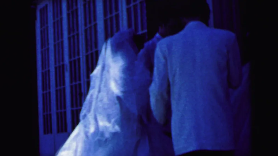 A close rear view shows the bride and groom paused near the entrance during a 1964 Camden wedding procession.