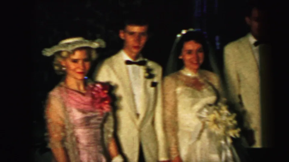 A 1964 Camden wedding group poses outdoors, including the bride, groom, a woman in a pink dress and hat, a young boy, and a man in a light jacket.