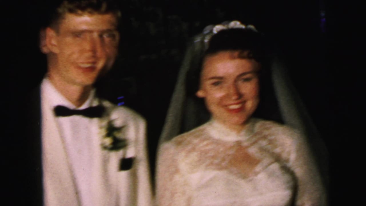 In supported 1964 Camden wedding footage, the bride and groom smile toward the camera in formal reception attire.