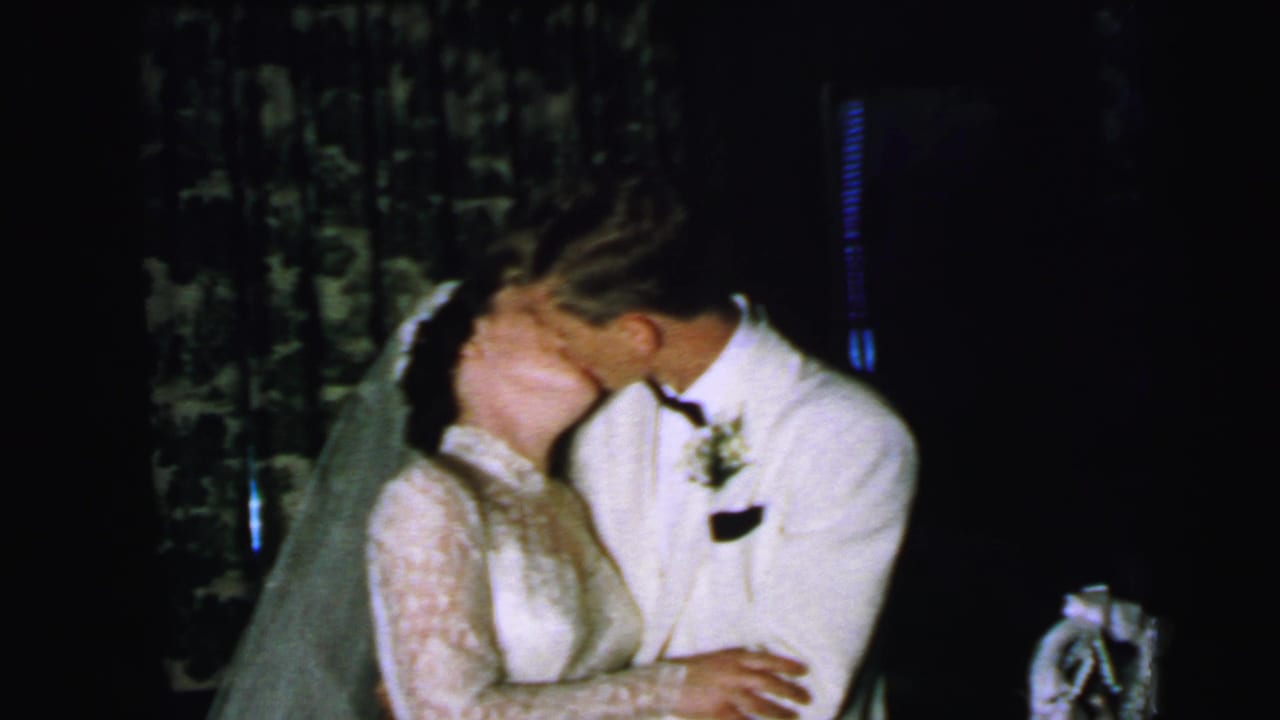 The newly married couple continue a close kiss in the 1964 Camden wedding scene, with the bride's veil and the groom's boutonniere visible.