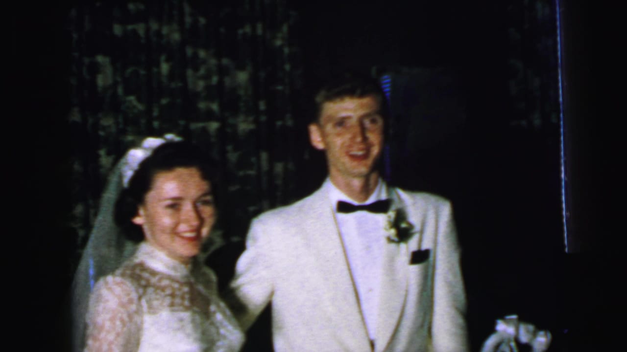 Bride and groom stand side by side indoors, smiling toward the camera.