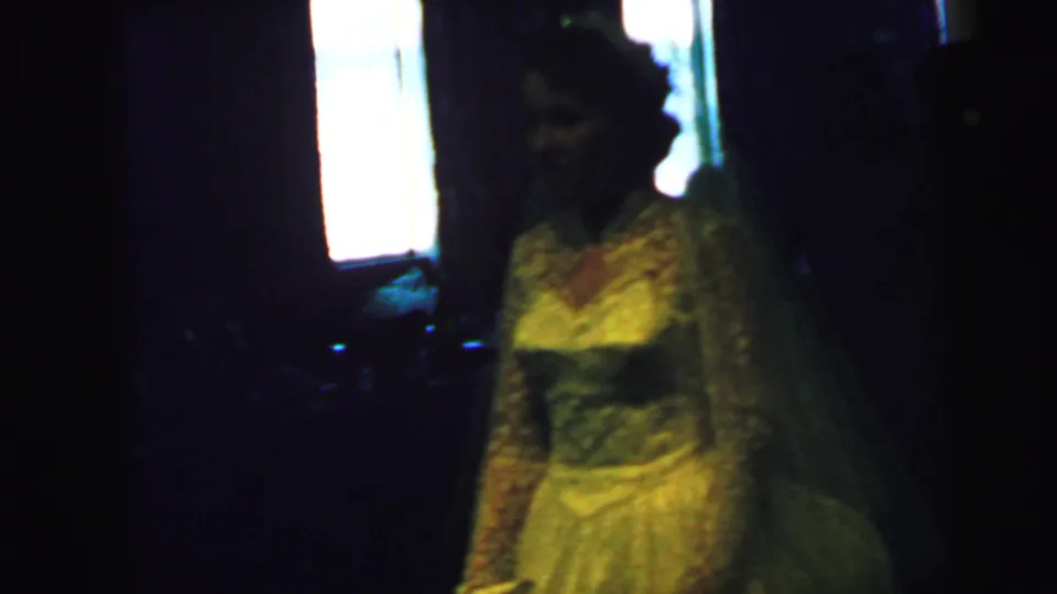 A shadowed view of the Camden wedding bride shows her lace gown, veil, and bouquet in soft, grainy 8mm focus.
