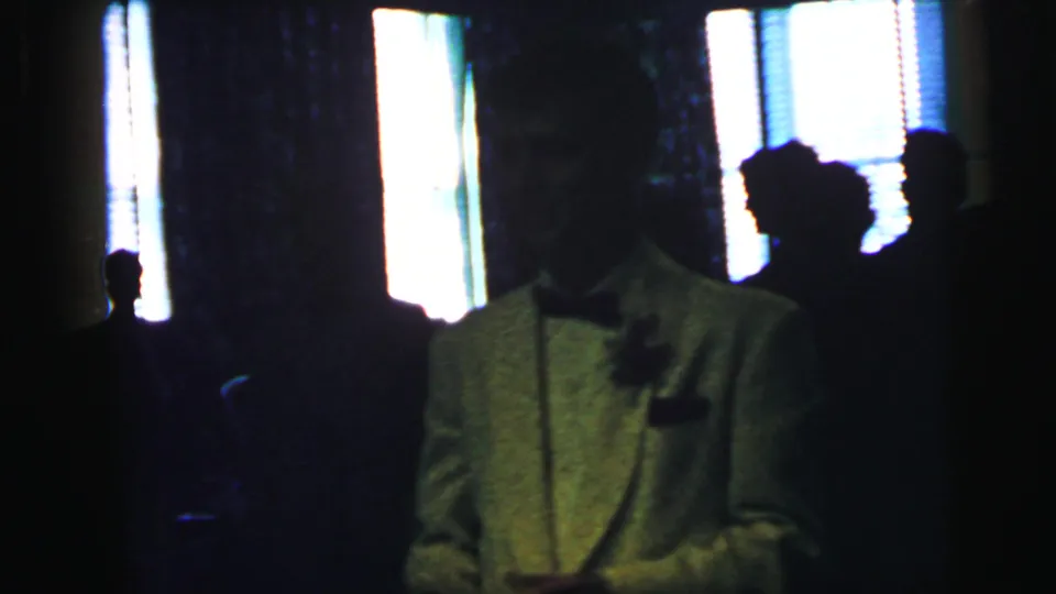 The formal-event scene continues with a white-jacketed man at right and dark guest silhouettes against bright interior windows.