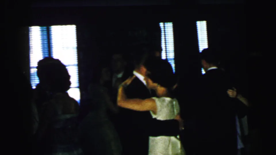 Adults appear in close partner dances at a 1964 Camden party, with most figures silhouetted by bright window blinds.