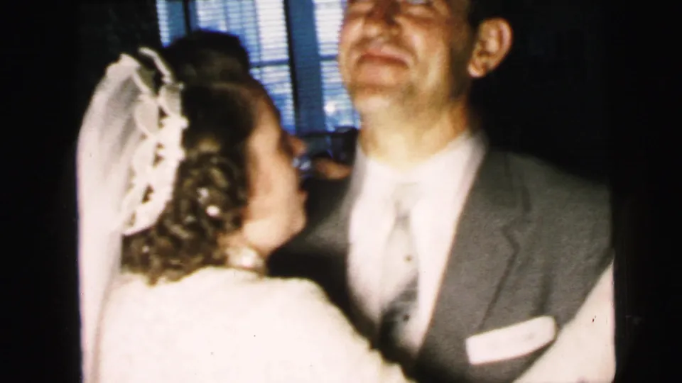 Close 8mm view of a bride in veil and gown dancing with a suited man during the Camden wedding reception.