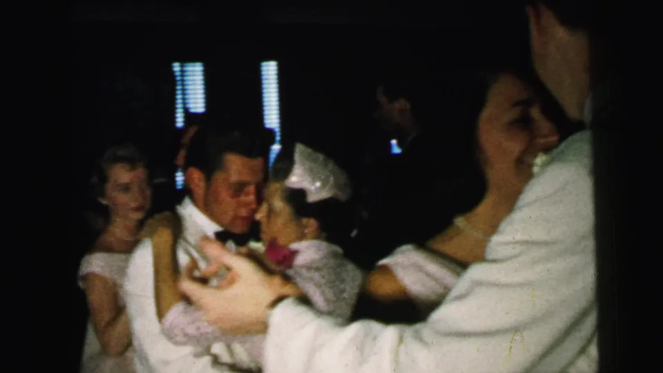 1964 Camden indoor dance frame with several formal-dressed couples, including a close foreground pair and guests in the background.