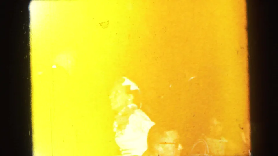 A strong yellow film flare partially covers a woman and guests inside the Camden wedding reception, with details softened by exposure.