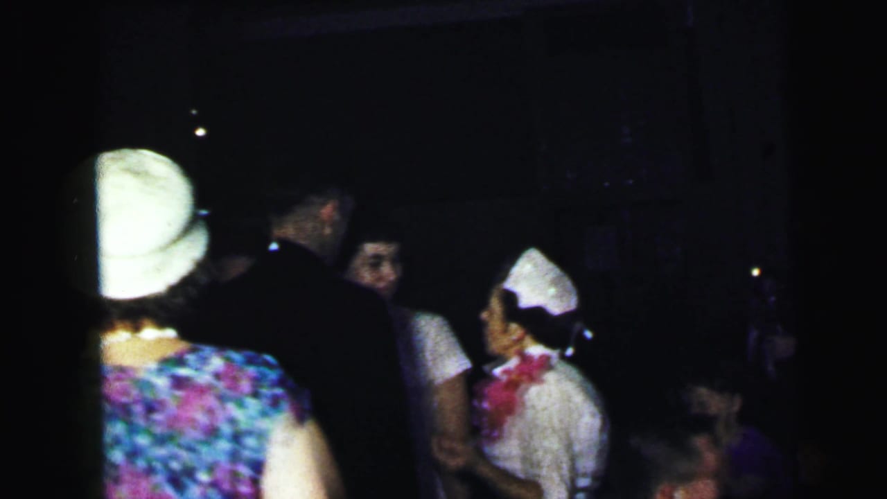 Guests seen from behind and in profile inside a dark reception space.