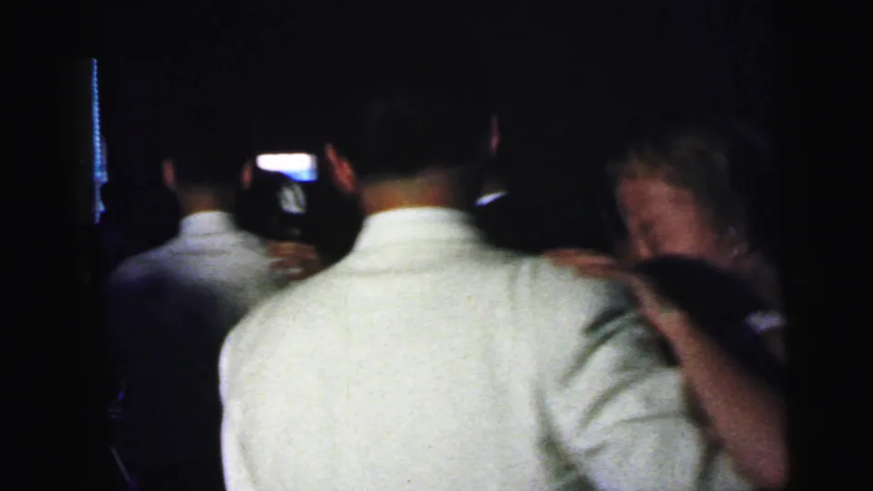 In the supplied Camden party footage, the camera looks over a man in a light shirt toward nearby guests and a partially visible woman.