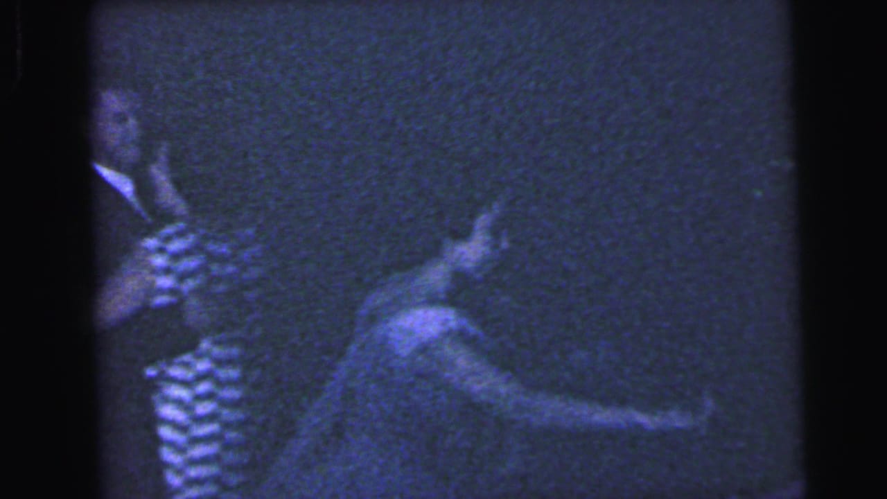 Blue-tinted frame of guests dancing, with a striped dress visible at left.