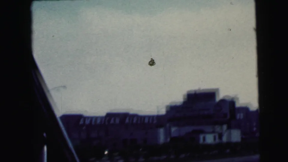 1964 Camden roadside frame showing an airport-related building with visible American Airlines signage, seen through a car window.