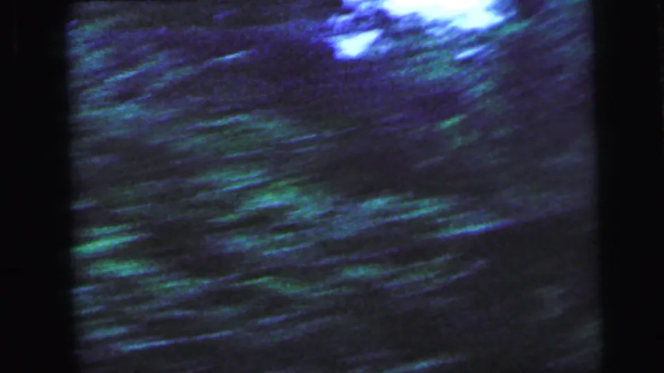 Abstract 8mm home movie frame from 1964 showing streaked green and blue vegetation, likely passing foliage filmed from a moving vehicle near Camden, New Jersey.