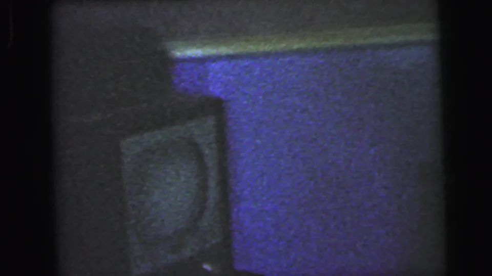 Bathroom interior with a strong purple color cast, a curved fixture at lower left, and a horizontal ledge, 8mm home-movie film circa 1964.
