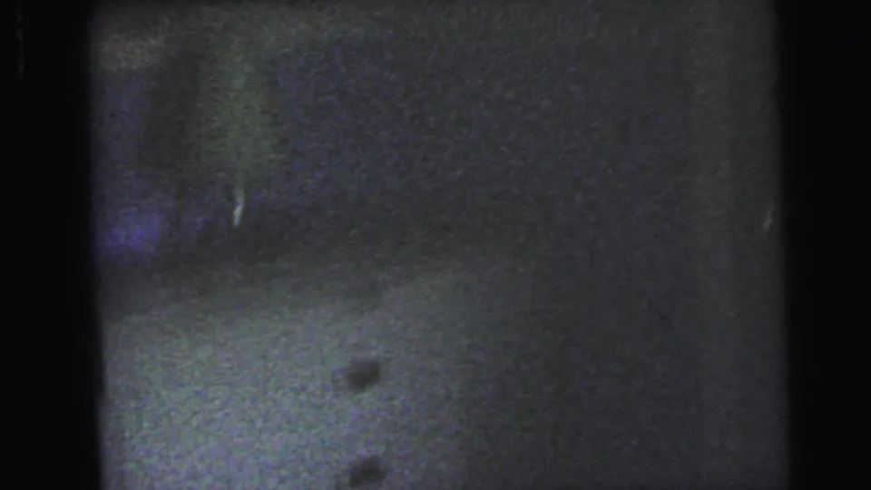Near-black underexposed interior, possibly a floor or flat surface, with faint purple color shift, 8mm home-movie film circa 1964.