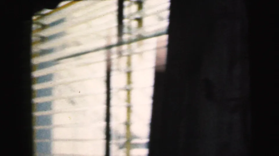 8mm home movie frame showing an exterior building through venetian blinds, likely Camden, New Jersey, circa 1964