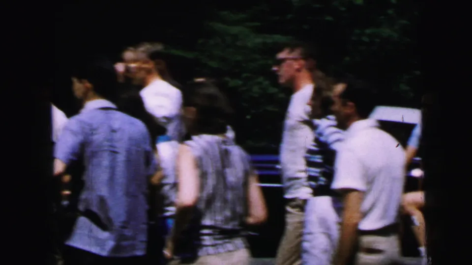 Men in white shirts, one in glasses, one in a striped shirt, conversing at an outdoor gathering, circa 1964 8mm home movie, Camden, New Jersey.