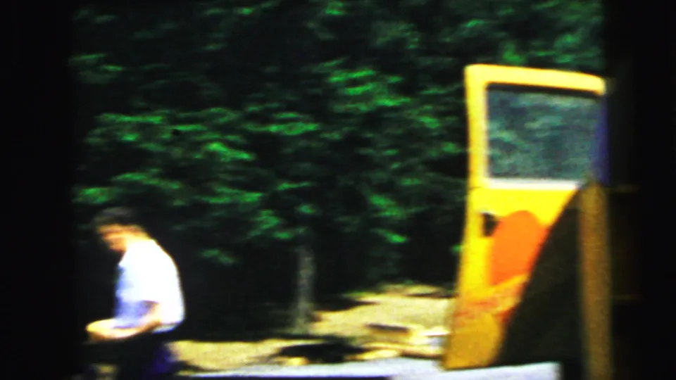 A bright yellow novelty sightseeing vehicle with an open side door among dense summer trees; a person in a white shirt stands in the foreground, circa 1964.