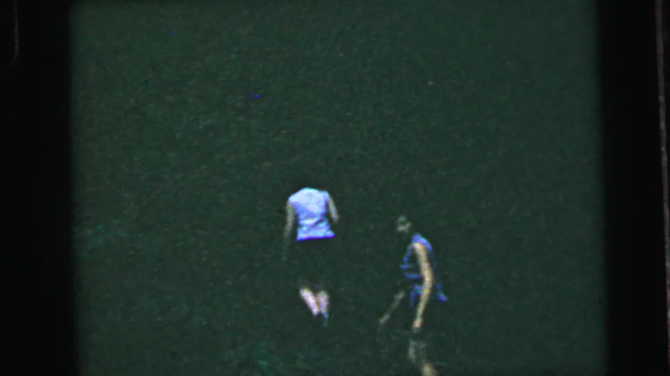 Two women in light summer clothing moving across a grassy slope, 8mm home movie, United States, circa 1964.