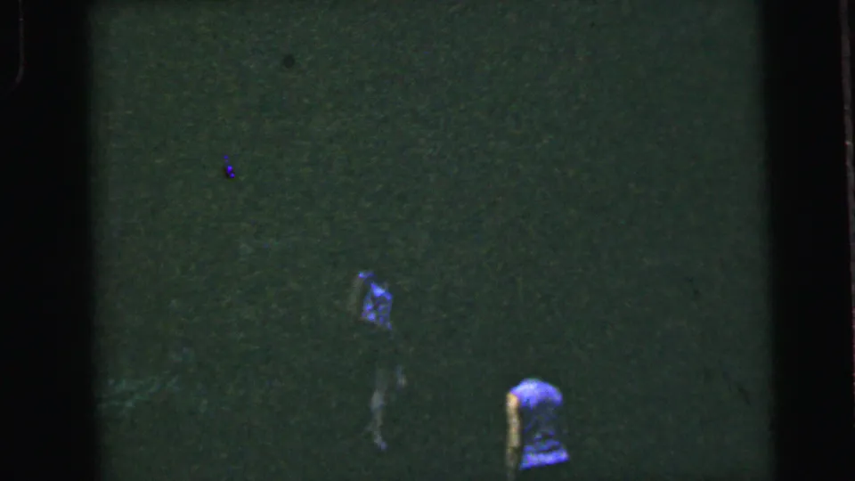 Two women in blue tops in a dark wooded setting in what appears to be a mid-1960s 8mm home movie, attributed to Camden, New Jersey.