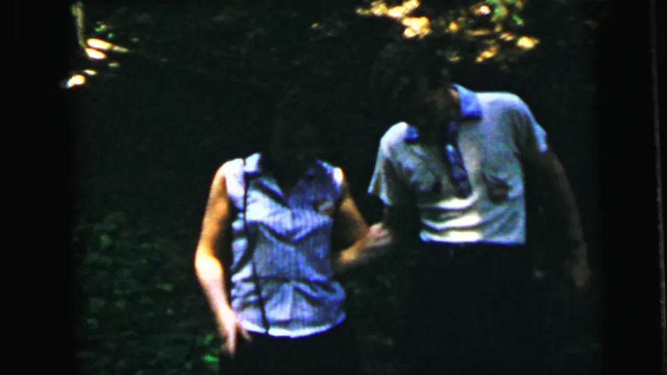 Young couple in close shot walking through summer woodland on 8mm film, faces partially visible, circa 1964, Camden, New Jersey.