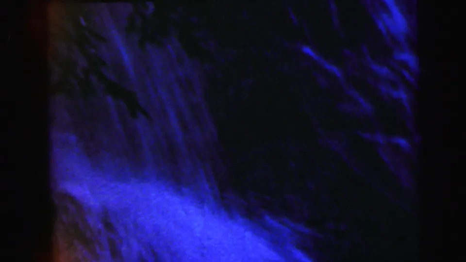 Mid-pan 8mm frame from 1964 showing a waterfall close-up with heavy blue-purple dye shift and streaking white water against a dark backdrop.