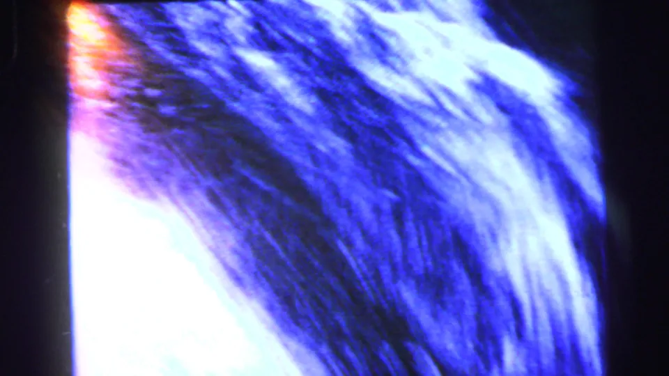 1964 8mm close-up of a rushing waterfall with prominent white foam, blue tone, and an orange light leak bleeding in from the upper-left edge.