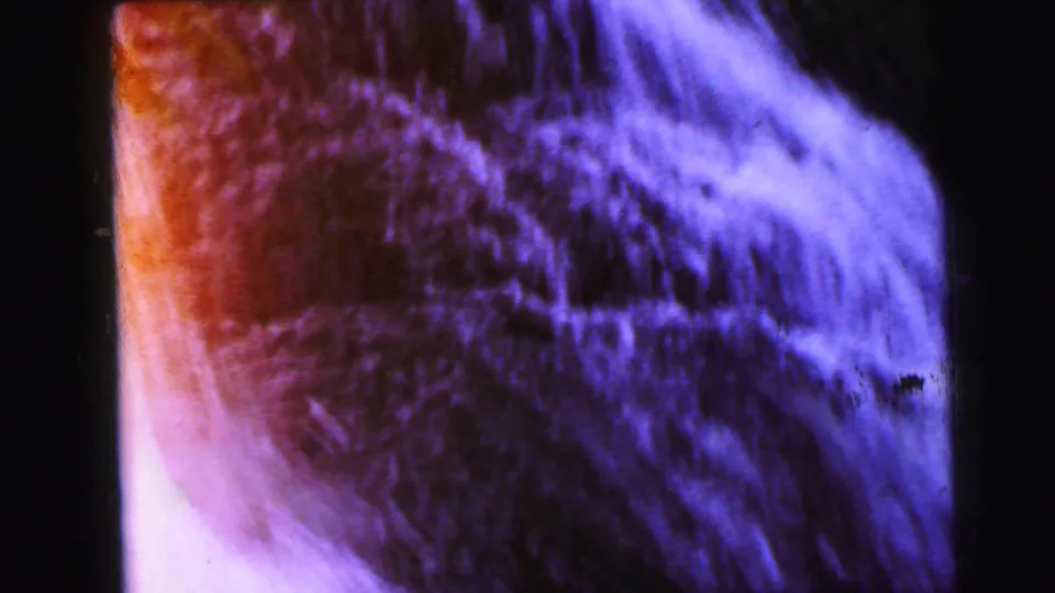 Final frame of the 1964 8mm upward pan showing contrasting warm rust-orange tones on the left and blue-purple cascading water on the right.