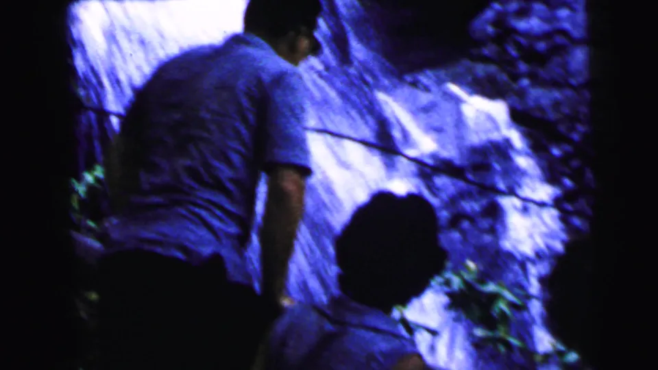 Man in blue shirt from behind at a rocky waterfall, second figure partially visible, 8mm home movie circa 1964, Camden, New Jersey