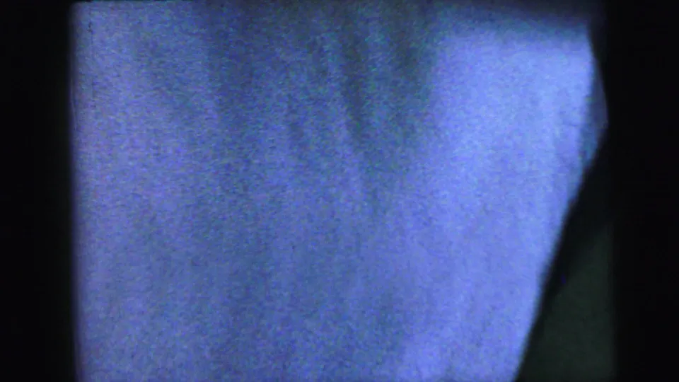 Near-blank closing frame from an 8mm home movie reel showing soft blue-lavender tone; a partial structural edge is visible at right, consistent with reel run-out circa 1964.