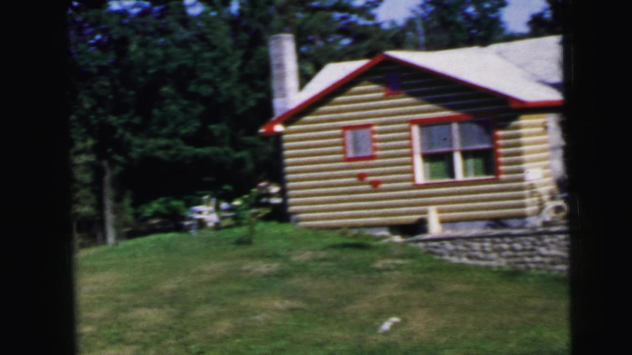 Log cabin exterior with cylindrical chimney, red roofline and window trim, stone wall, 8mm film.