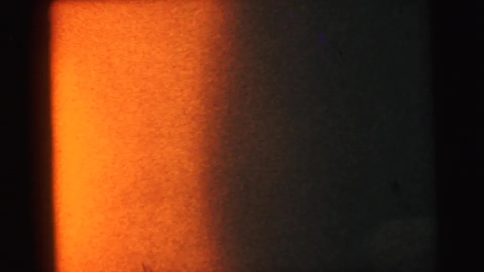 8mm film light-leak flare showing an intense orange-amber wash with dark vignette edges, characteristic of exposed or improperly loaded film stock.