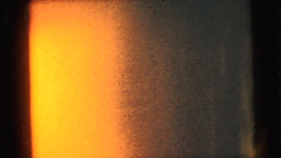 8mm film showing a dissipating orange light-leak transitioning to darker tones at right, indicating end-of-reel or film damage.