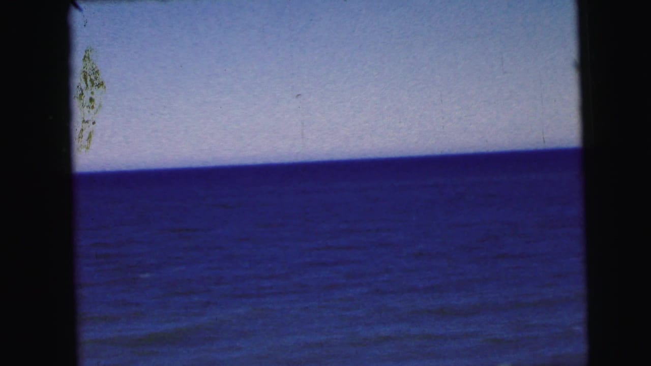 Static ocean horizon on 8mm film, circa 1964, attributed to a New Jersey coastal location; emulsion damage and heavy vignette visible.