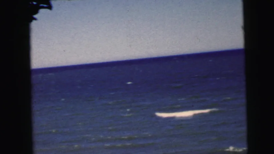 Final 8mm frame circa 1964 showing open ocean attributed to a New Jersey coastal location; a prominent whitecap or breaking wave appears in the lower right.