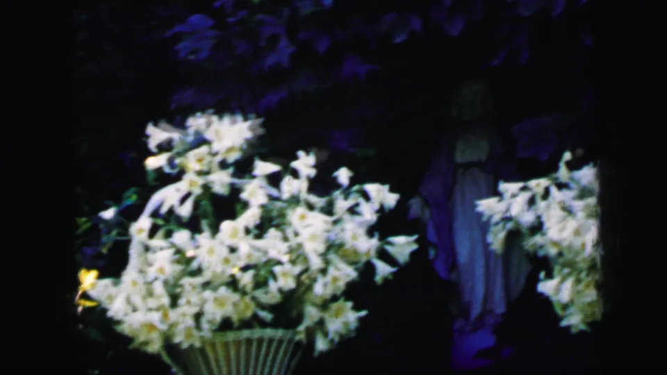 Camden, New Jersey 1964 frame with a bright white flower arrangement and a partially obscured robed statue.