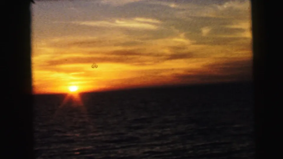 A warm sunset over open water fills the frame, with orange light and dark 8mm exposure at the horizon.