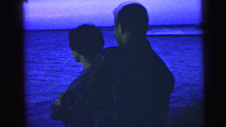 In the 1964 Camden, New Jersey metadata context, two silhouetted adults stand together by blue-tinted water and look toward the distant shore.