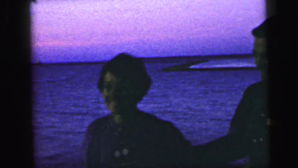 One adult turns toward the camera on the Camden waterfront while another person remains partly cropped at the frame edge.